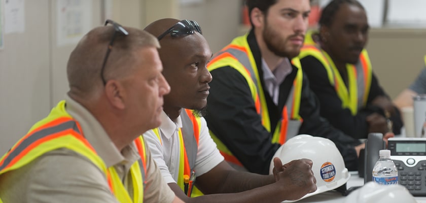 men sitting at table in construction safety outfits