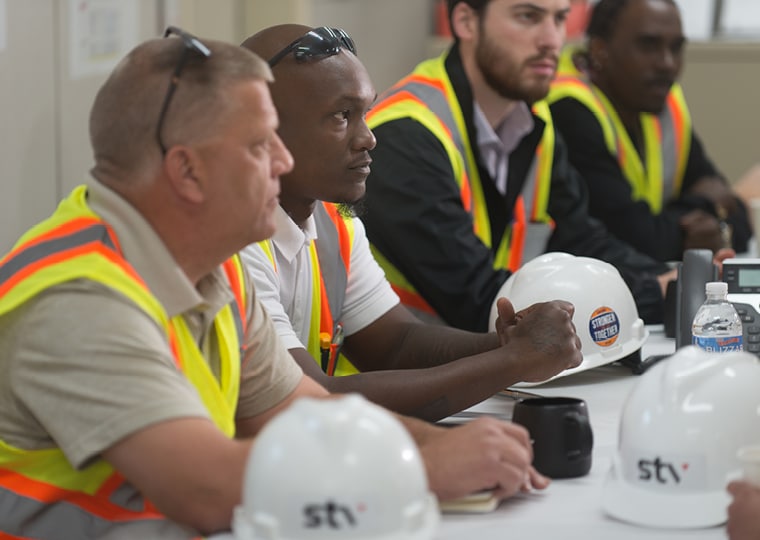 men sitting at table in construction safety outfits