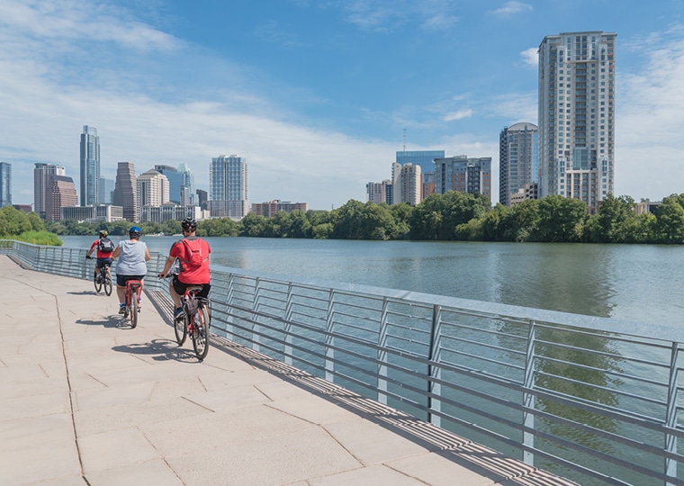 people riding bike alongside river on bridge